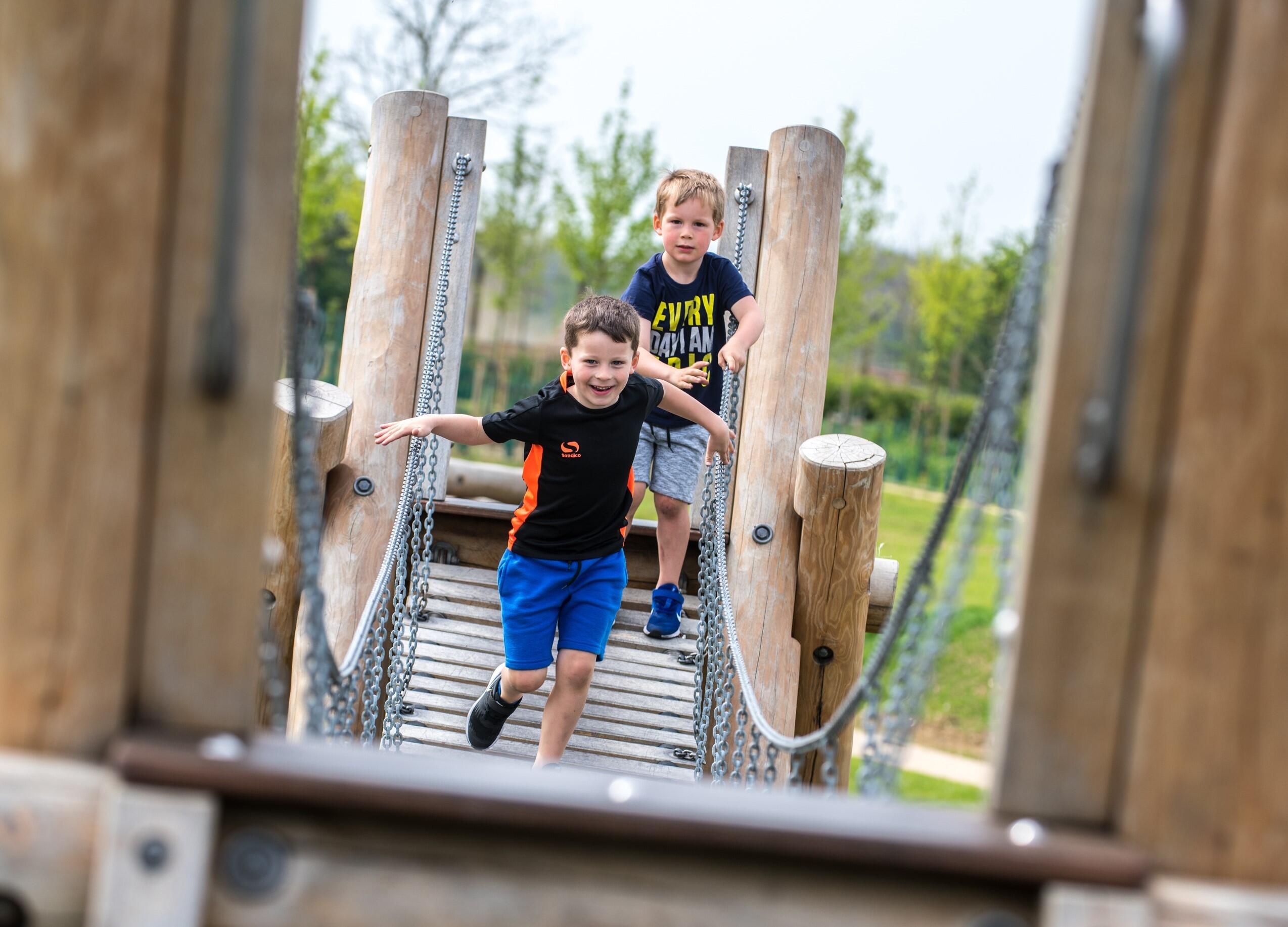 A photograph of children running along a wooden play bridge. © BMD