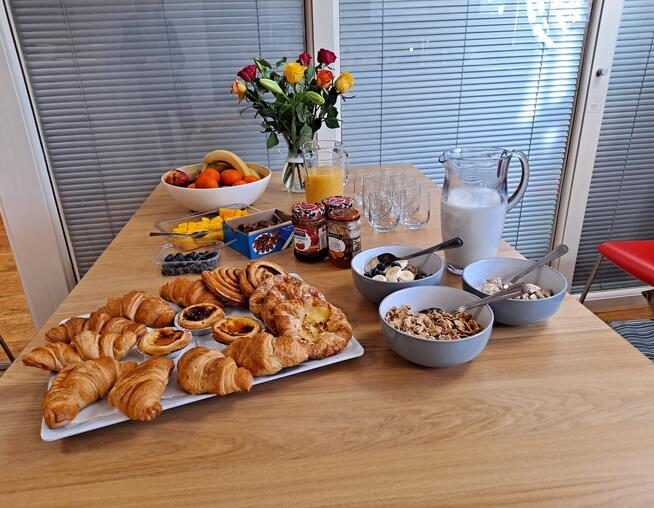 A photograph of a breakfast spread with fruit, cereals and pastries