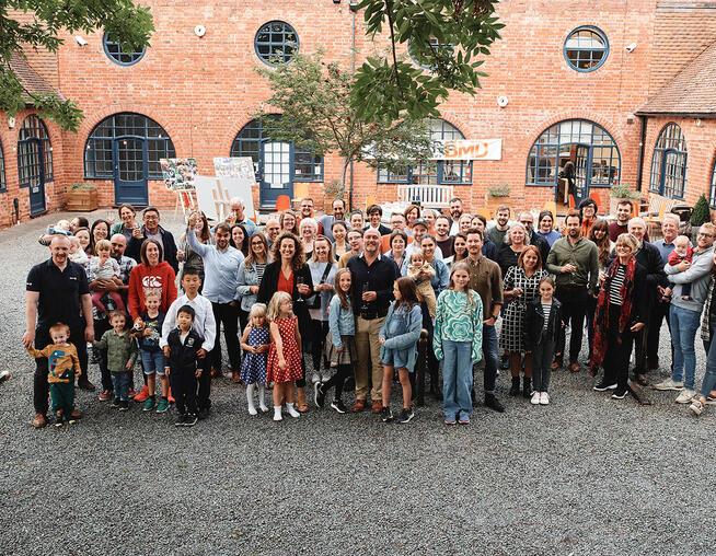 A group photograph of BMD employees standing in a courtyard